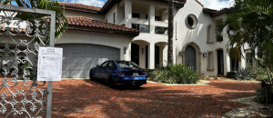 A property with a notice on it's front gate with a car parked behind the gate